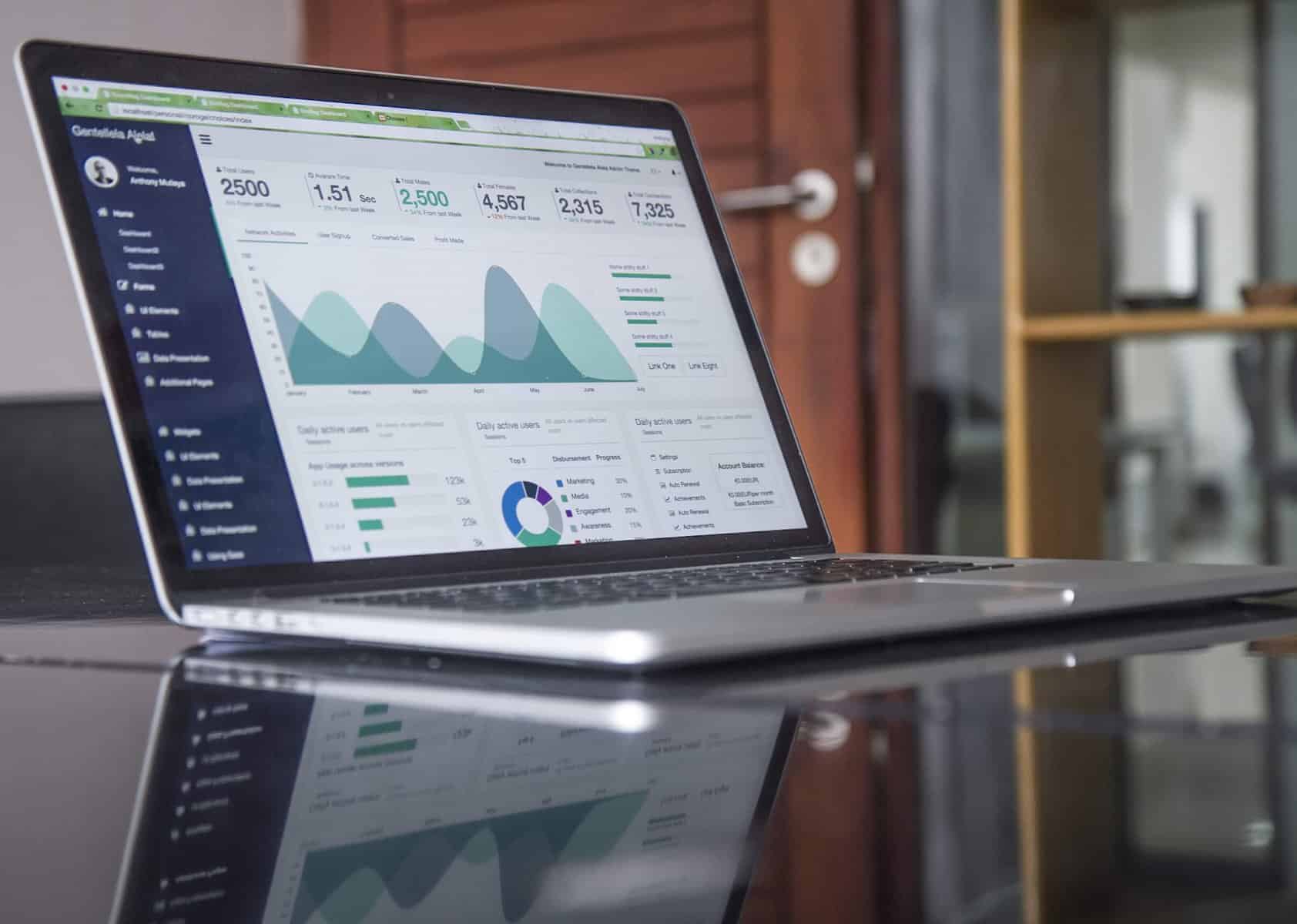 laptop computer on glass desk showing statistics